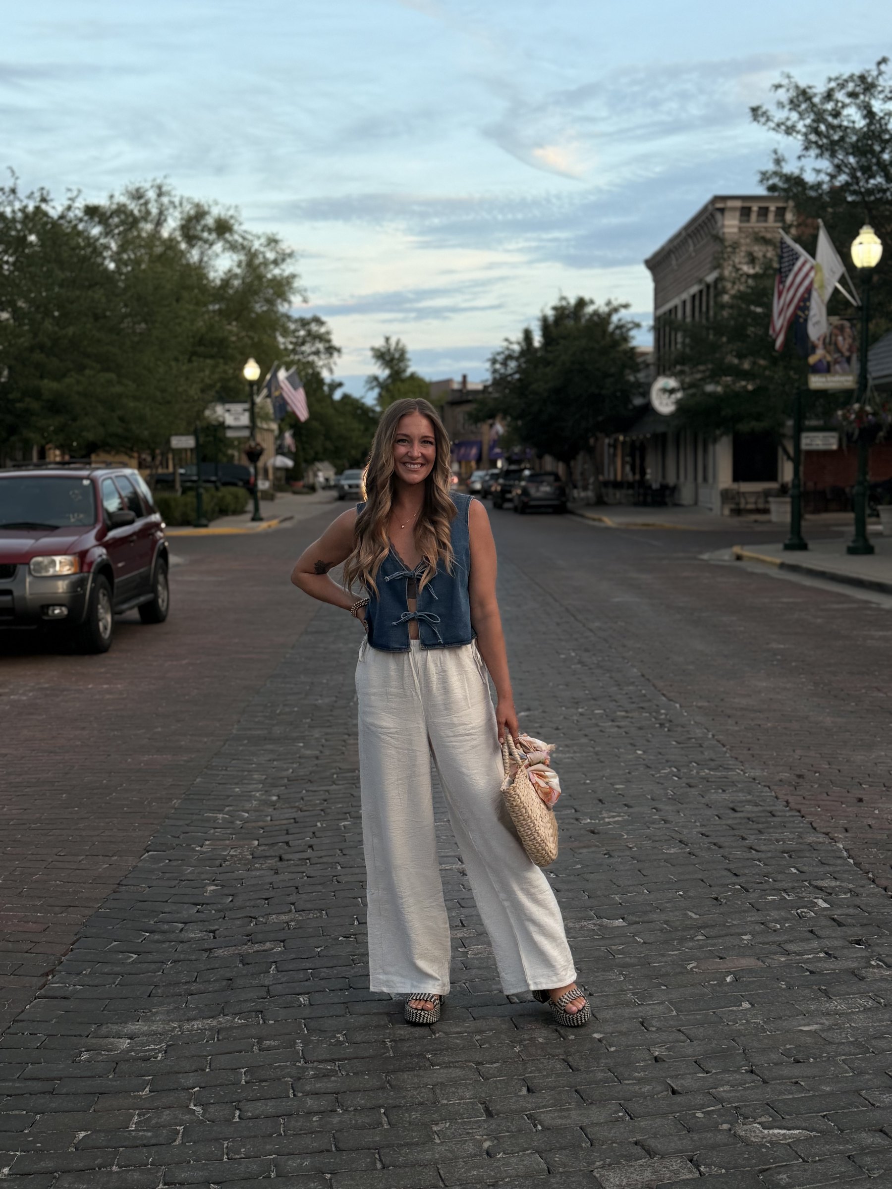 Liz standing on a brick main street in small town Indiana at dusk